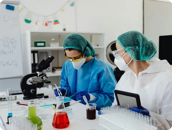 Two scientists in a laboratory setting with equipment and chemicals.